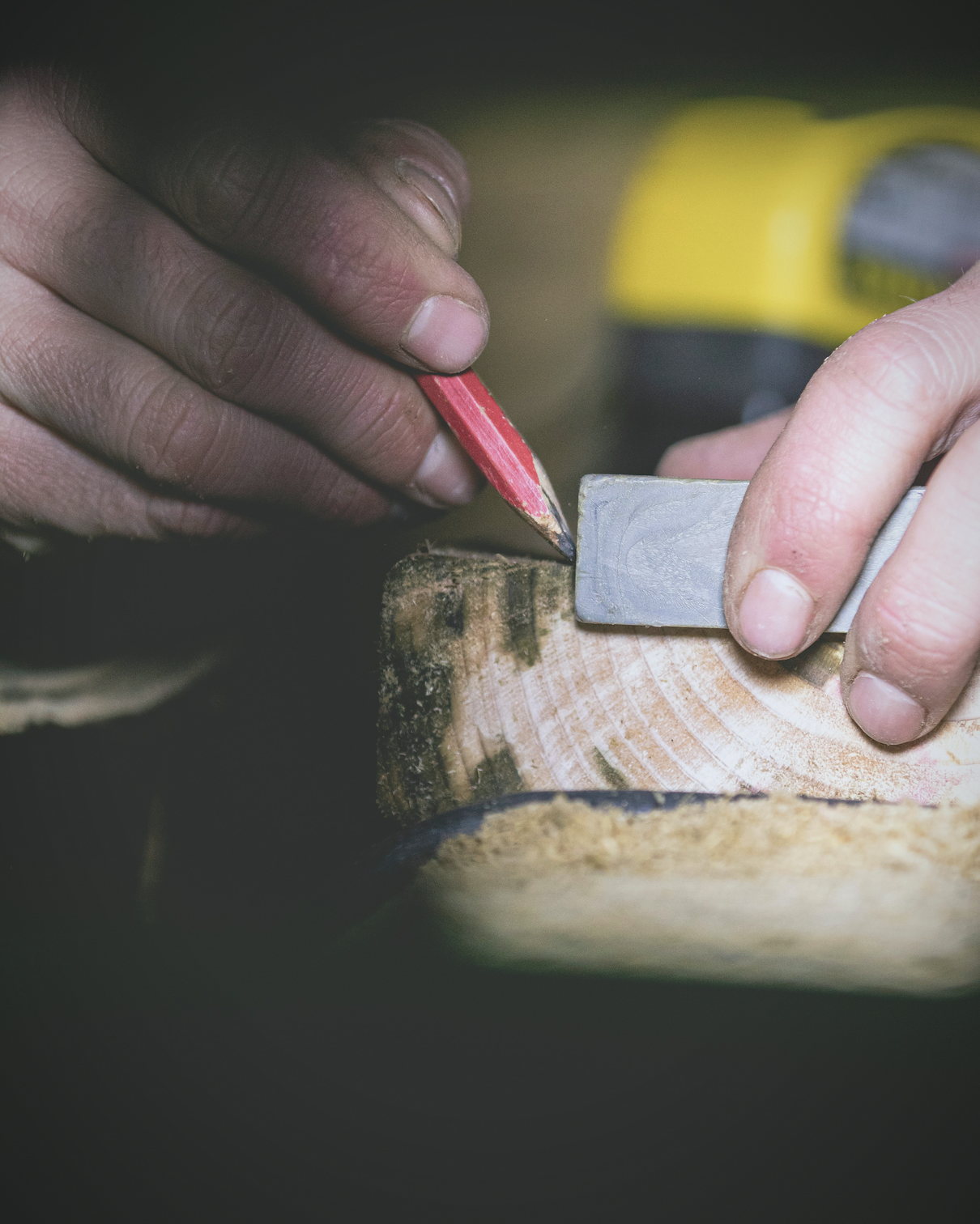 Mains traçant un repère au crayon sur une pièce de bois